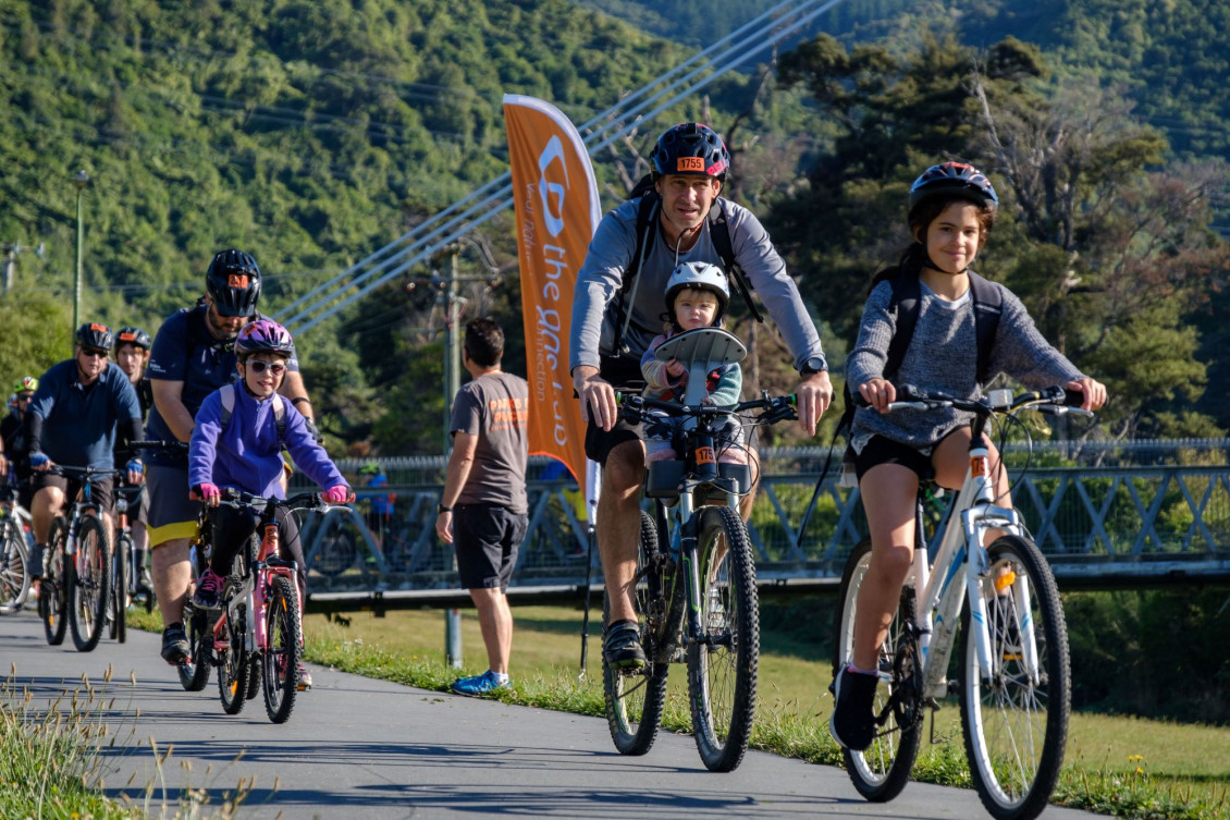 Cyclists on the trail, including children and a man with a baby in a carrier on his bike